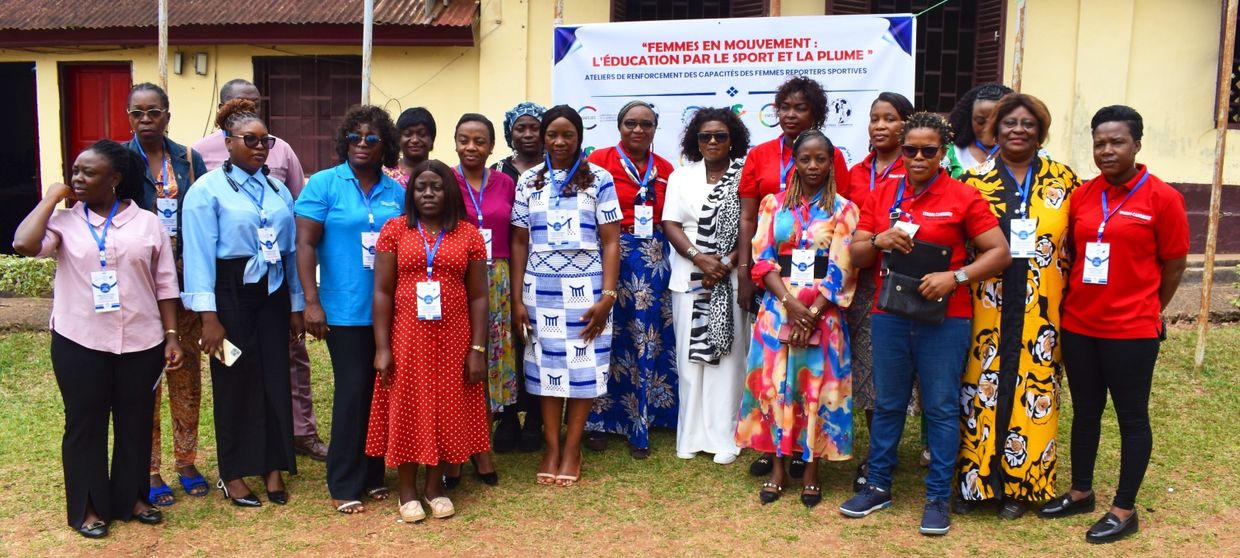 Photo de famille des participantes devant la banderole « Femmes en mouvement : l’éducation par le sport et la plume »